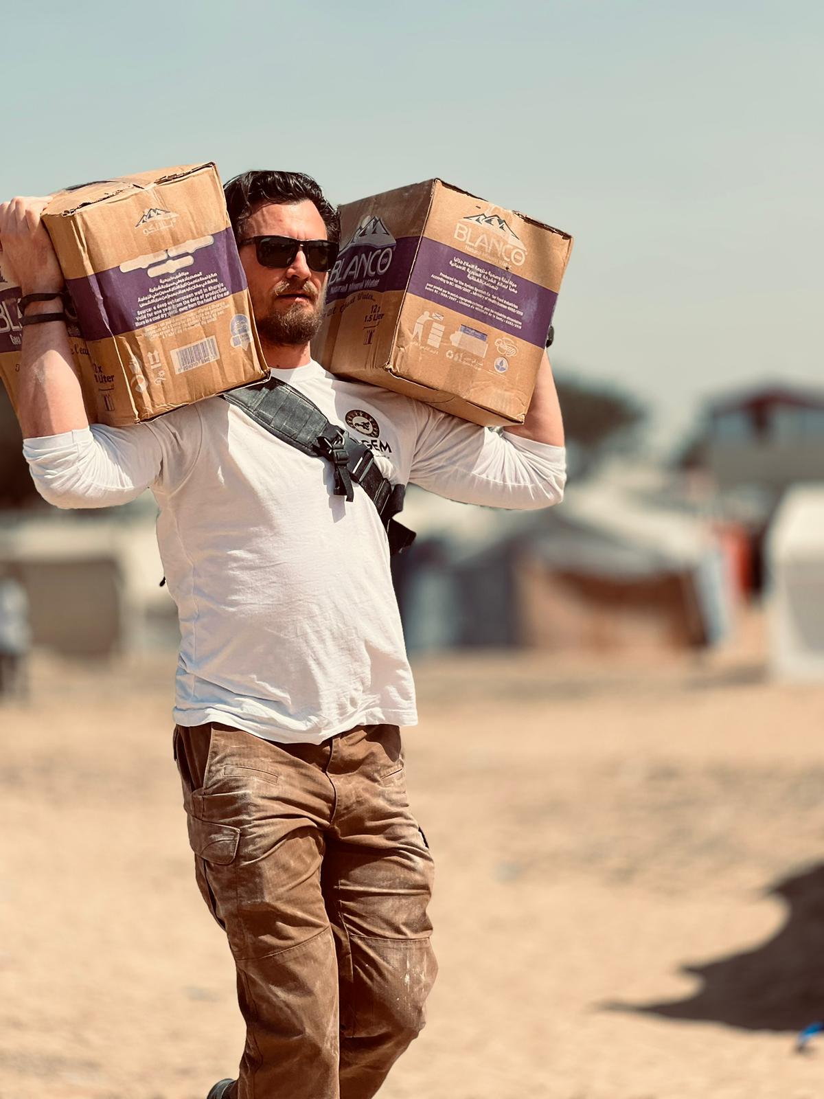 Carrying water boxes in a camp in Gaza