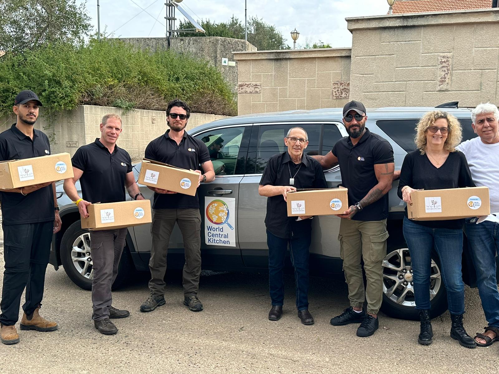 Team holding supply boxes at a World Central Kitchen vehicle